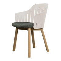 White slatted back chair with a dark green seat cushion and light wooden legs. Modern and minimalist design.