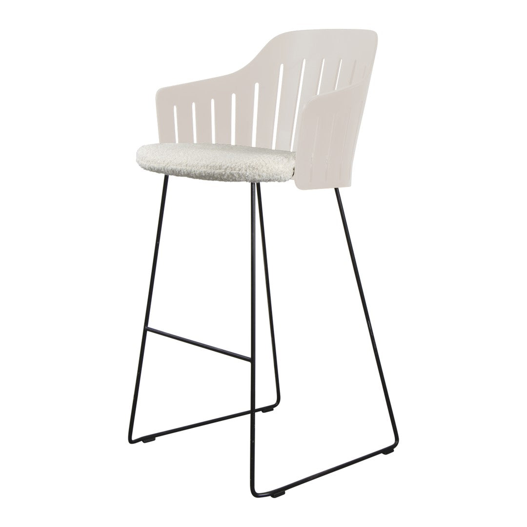 Stylish bar stool with a soft beige seat and a sleek, lightweight black metal frame, featuring a modern slatted back design.