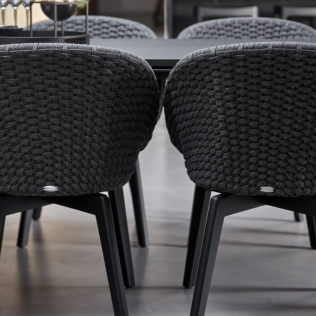 Two dark gray woven chairs with black legs in a dining setting.