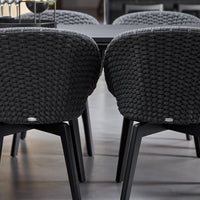 Two dark gray woven chairs with black legs in a dining setting.
