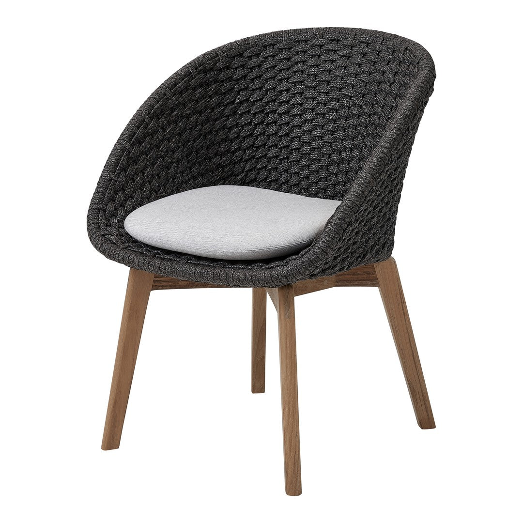 Black woven chair with a white cushion and wooden legs, showcasing a modern and stylish design.