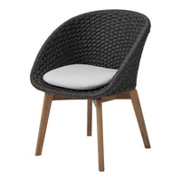 Black woven chair with a white cushion and wooden legs, showcasing a modern and stylish design.