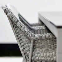 Gray woven patio chair with a sleek design, featuring intricate basketweave patterns and white cushion accents.