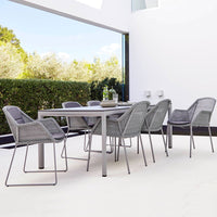 Gray woven chairs with minimalist metal frames around a light gray dining table, set on a neutral floor.
