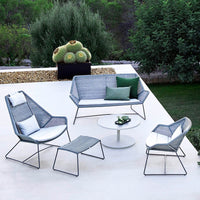 Modern outdoor seating set featuring gray tones and geometric patterns, complemented by white cushions and a round table.