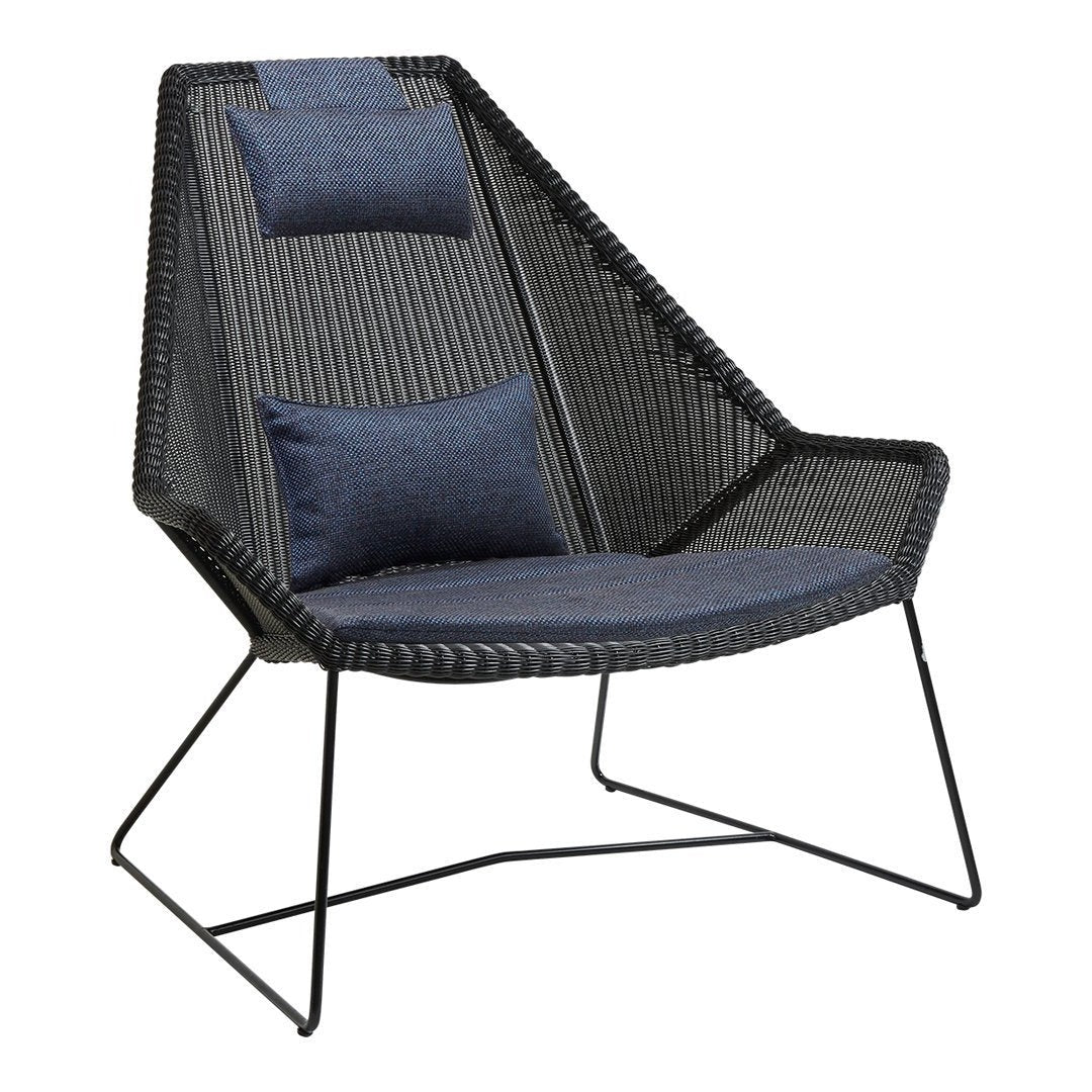Black woven chair with a stylish, angled silhouette and navy blue cushions featuring subtle texture.