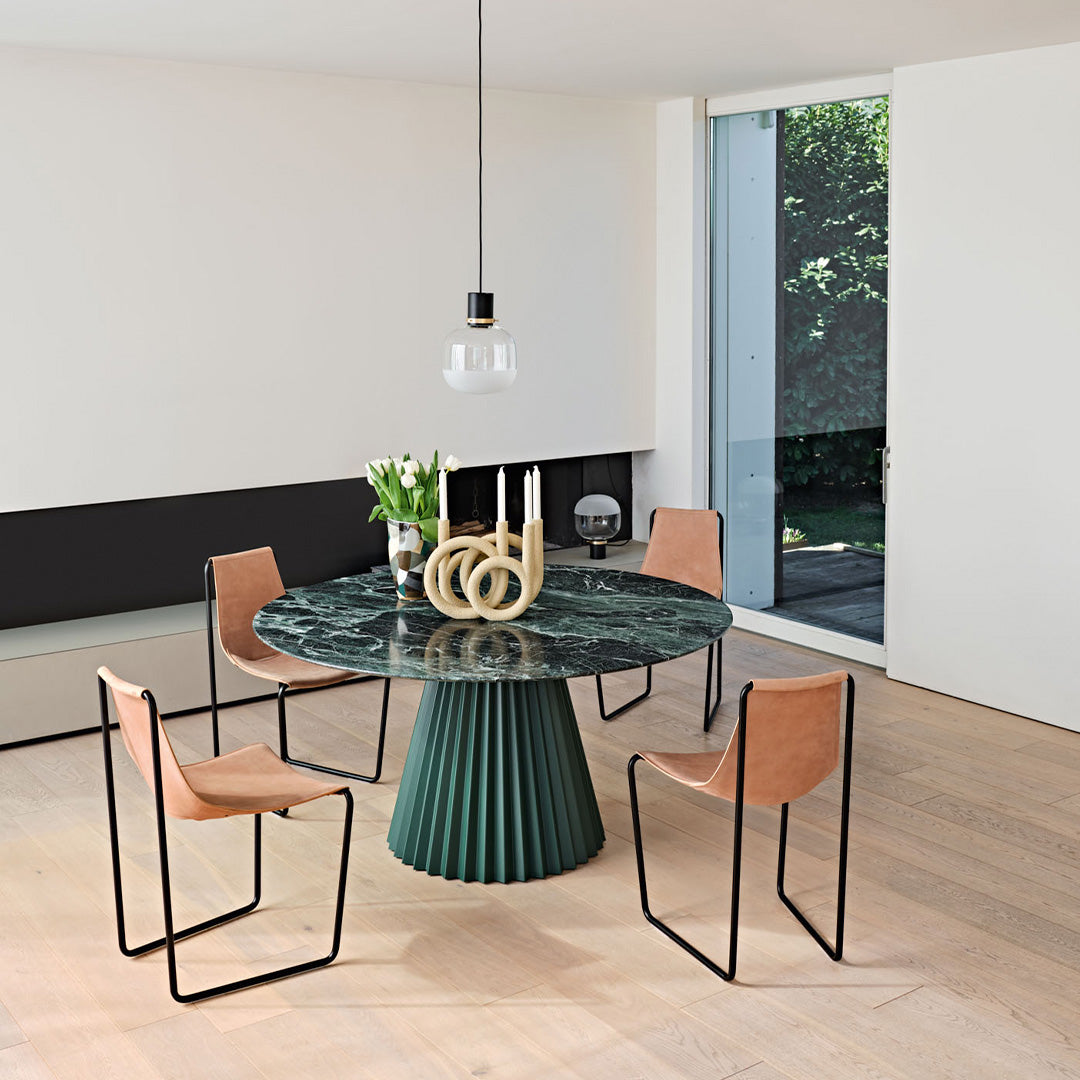 Elegant green marble round table with beige leather chairs, black accents, and a natural wood floor. Modern dining setup.