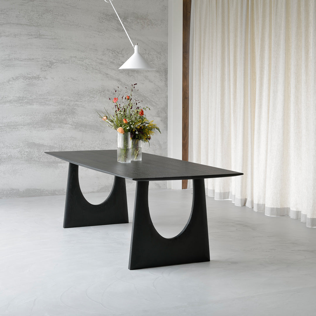 Sleek black dining table with a minimalist design and curved patterns, set against a light gray background.
