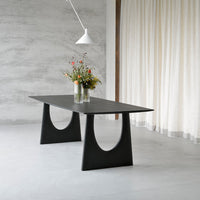 Sleek black dining table with a minimalist design and curved patterns, set against a light gray background.