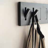 Black wall hook with hanging apron featuring bold white and black stripes. Modern and minimalist design.