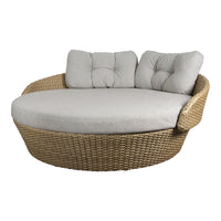 Round wicker lounge chair with light gray cushions, featuring a textured, natural woven pattern. Perfect for outdoor spaces.