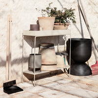 "Minimalist display table in soft beige with textured ceramic pots in earthy tones and sleek black accents."
