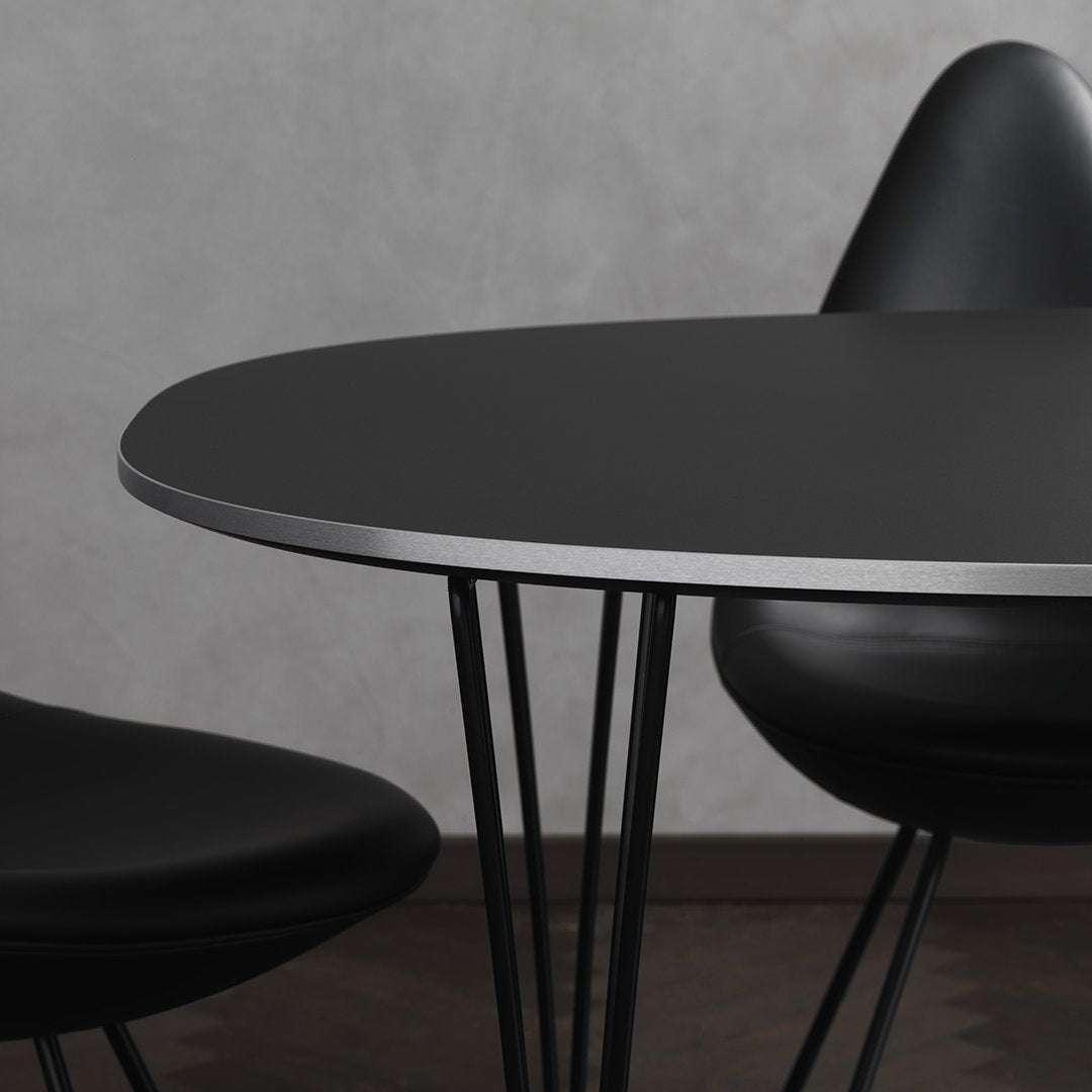Modern black oval table with sleek silver edge and minimalist black chairs, featuring smooth matte surfaces and clean lines.