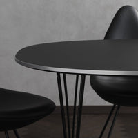 Modern black oval table with sleek silver edge and minimalist black chairs, featuring smooth matte surfaces and clean lines.