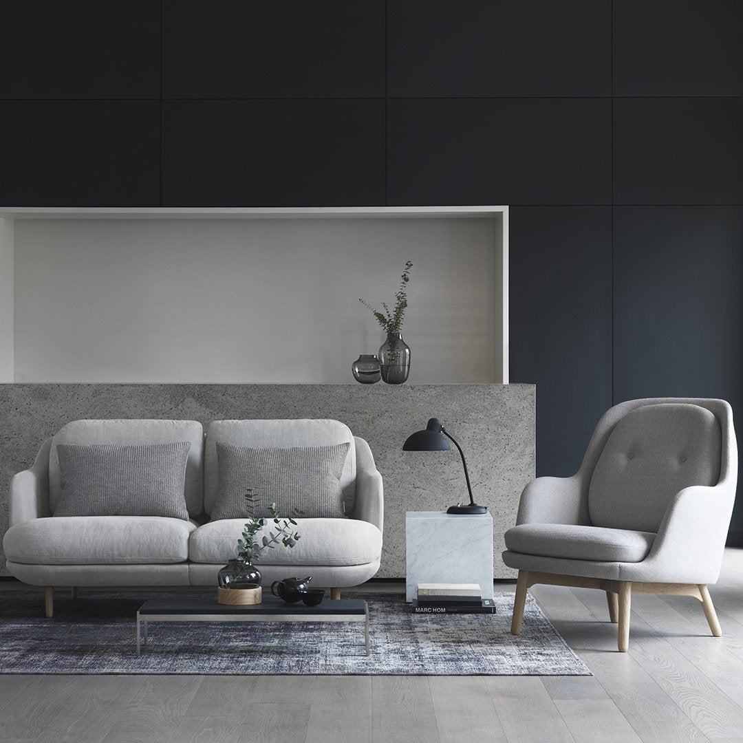 Light gray sofa with soft cushions and modern armchair, paired with a patterned rug in neutral tones.