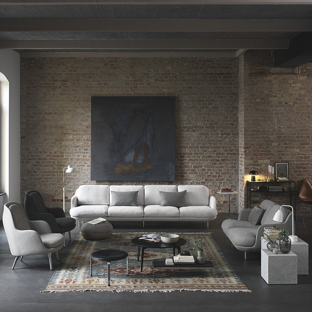 "Modern living room featuring gray furniture with geometric patterns on a vintage rug against a rustic brick wall."