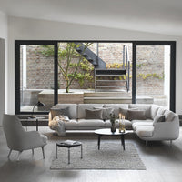Light gray sectional sofa with textured pillows, black metal accents, and a soft patterned rug in a modern living space.