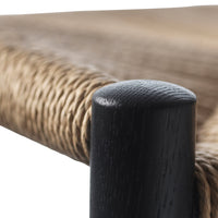 Black wooden leg with a textured finish, complemented by woven natural fibers in beige tones.