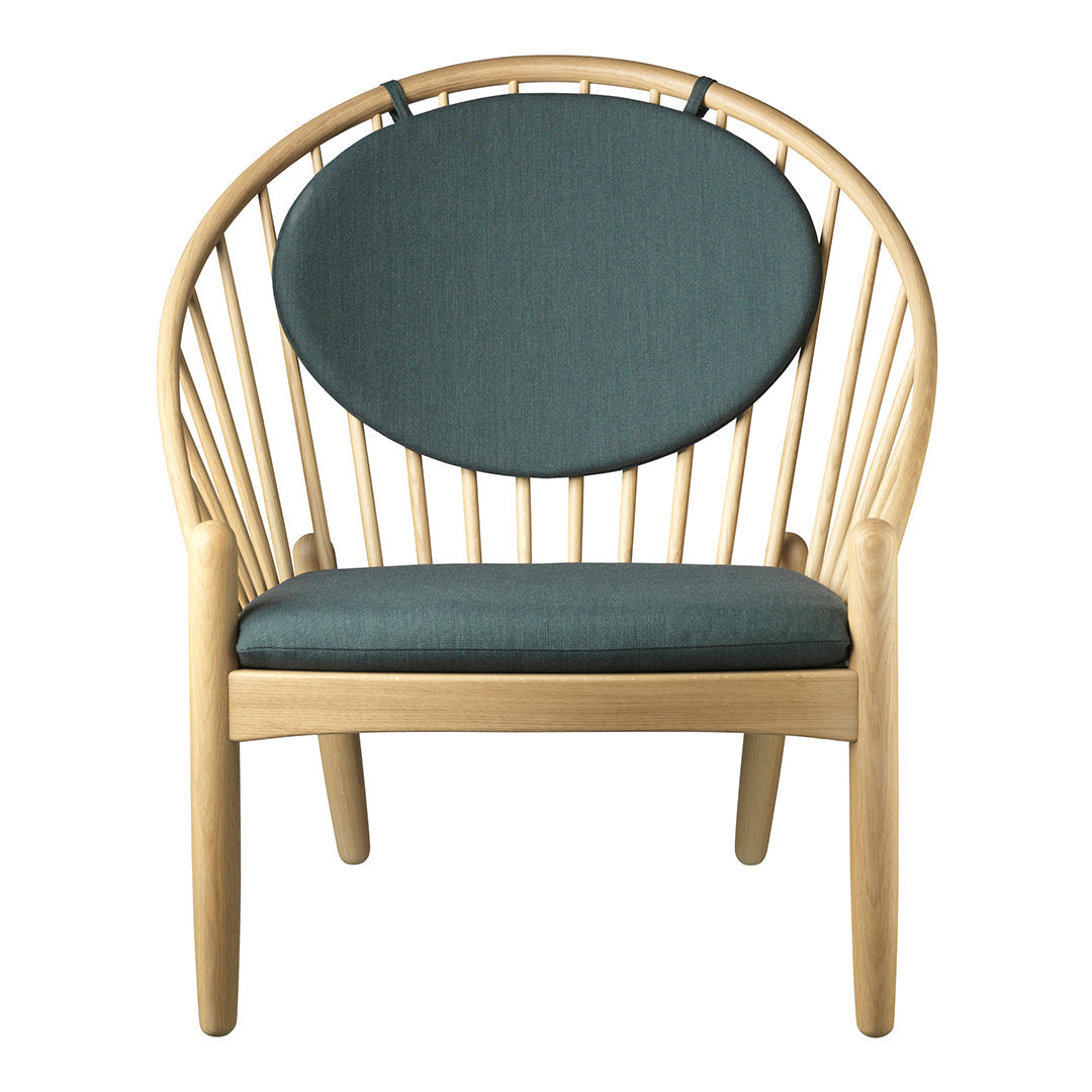 Natural wood chair with a curved back, featuring a soft teal cushion and round backrest accent.