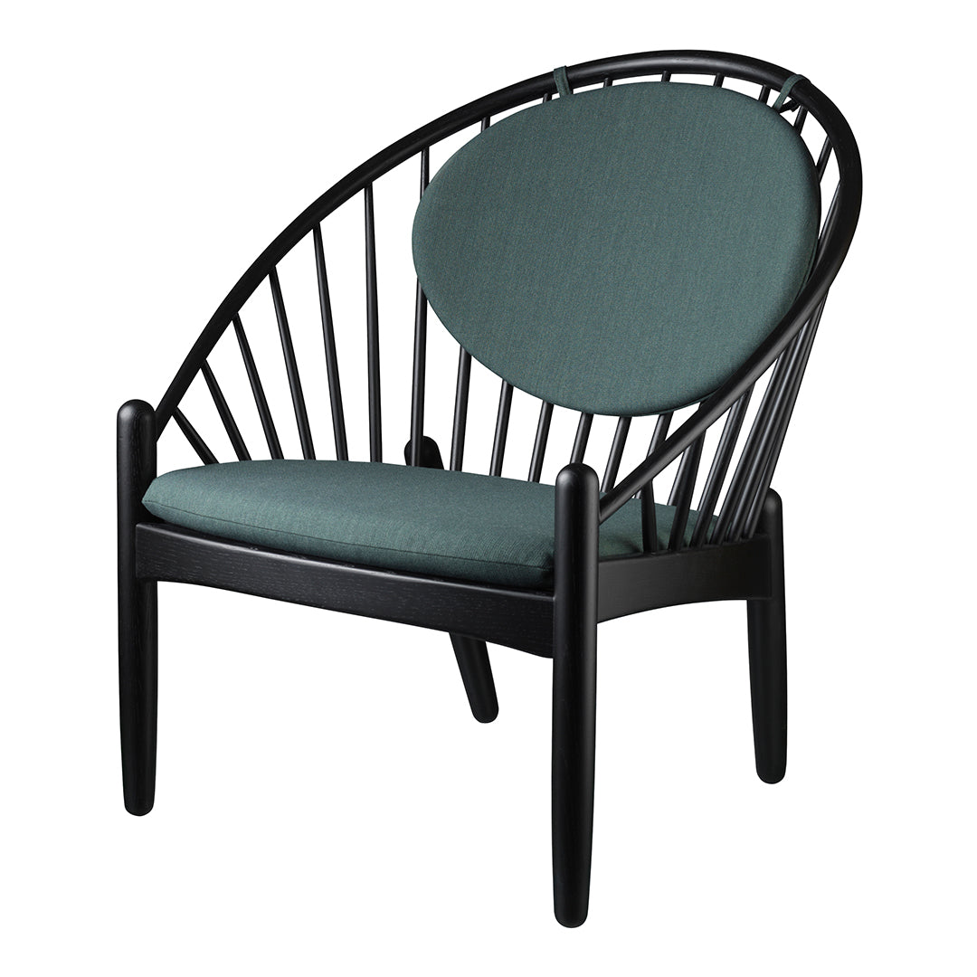 Teal cushion with a circular backrest on a sleek black wooden chair, featuring a contemporary spindle design.