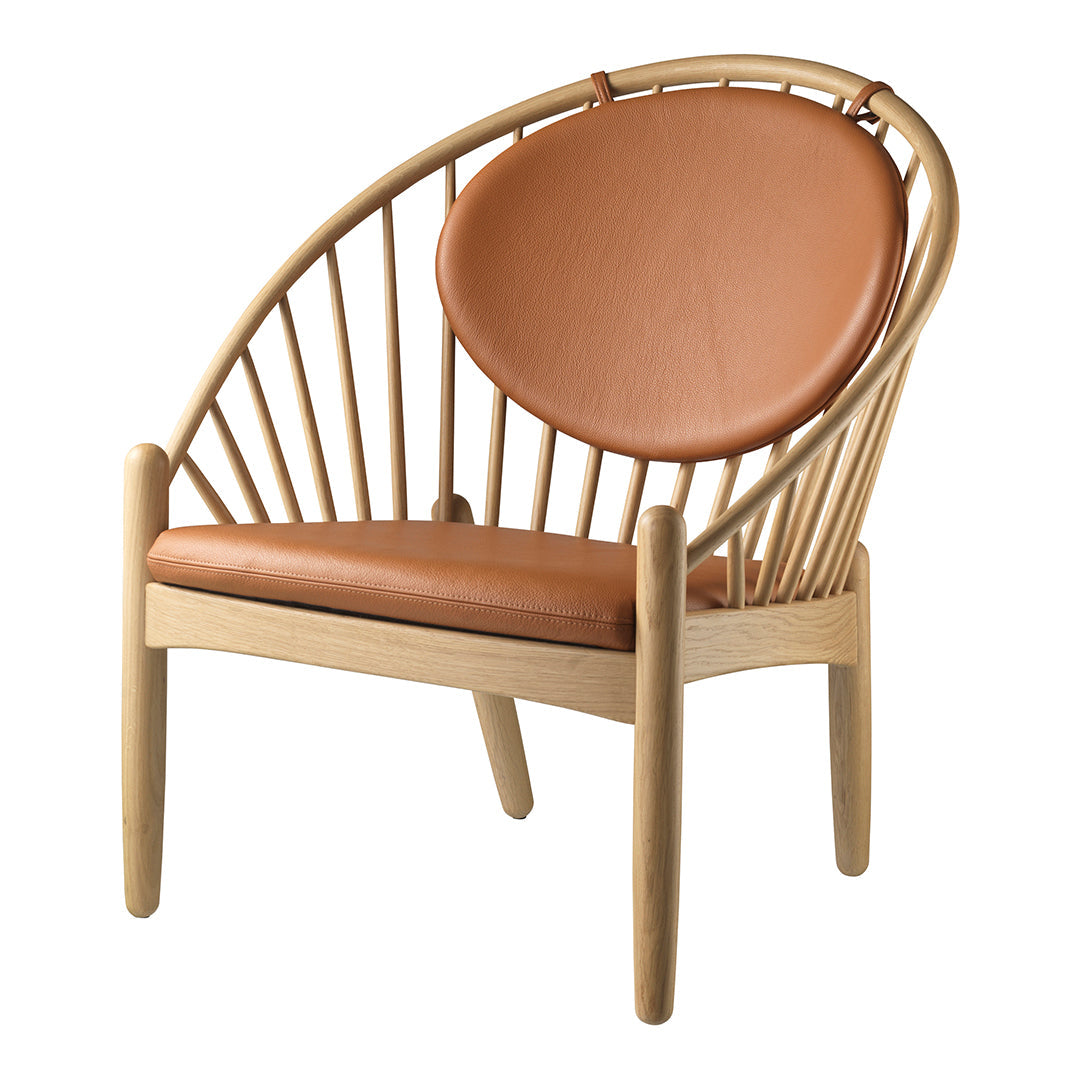 Mid-century modern chair featuring a natural wood frame and caramel leather cushion. Elegant curved design and minimalist style.