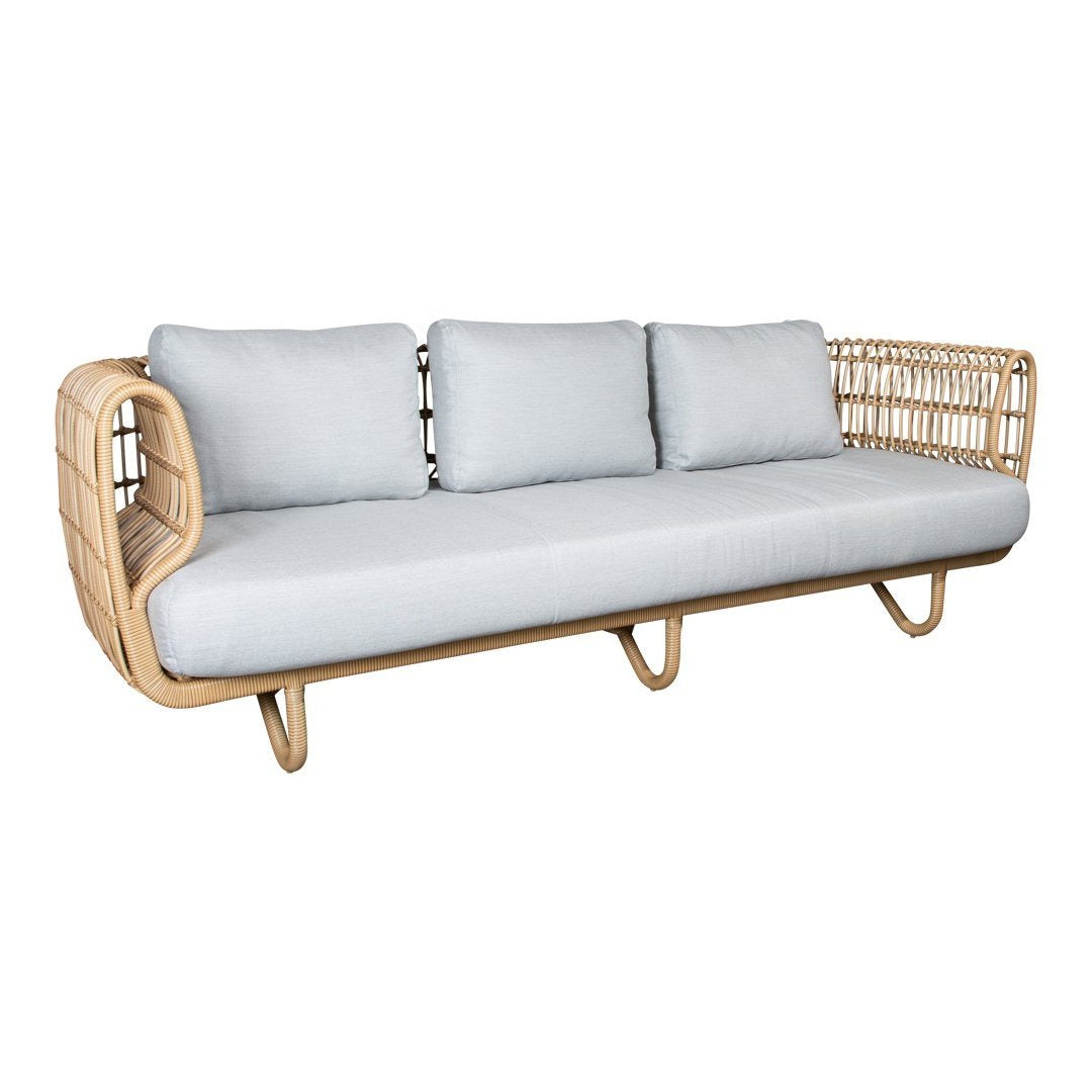Light blue cushions on a natural rattan sofa with an elegant woven design. Perfect for modern interior decor.