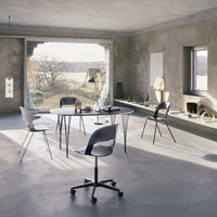 Modern dining room featuring grey tones, white and black chairs, and a sleek round table against a minimalist backdrop.