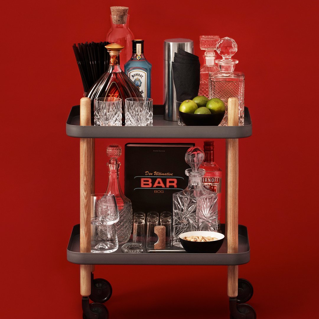 "Stylish bar cart with clear crystal glassware, black accents, and rich red backdrop, featuring green limes and elegant patterns."