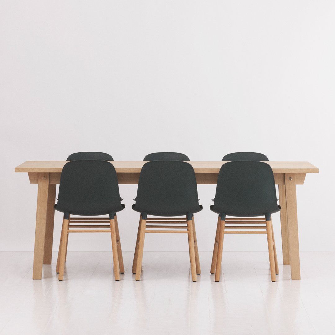 Modern wooden dining table with six black chairs featuring a sleek design and light wood finish.