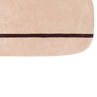Soft pink area rug with a dark brown accent stripe along the edge, adding a stylish touch to any room.