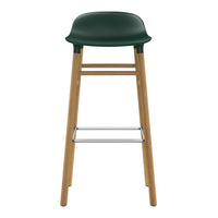 Green molded seat bar stool with natural wood legs and a sleek chrome footrest, perfect for modern decor.