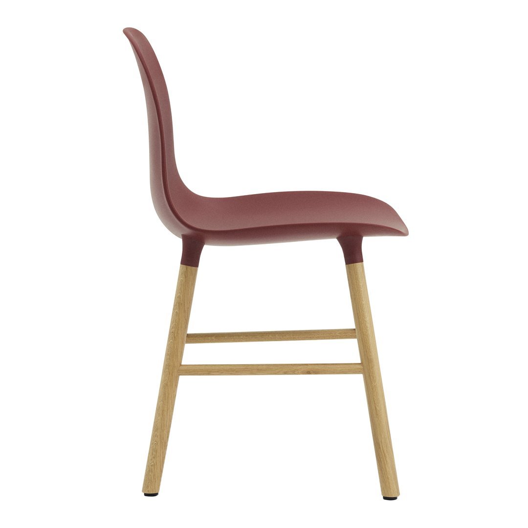 Side view of a sleek, burgundy chair with a light wood base, showcasing a modern color contrast and smooth curves.