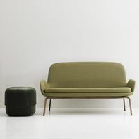 Olive green sofa with a smooth texture and matching green ottoman, set against a minimalist white background.