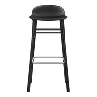 Black bar stool with a smooth, curved seat and sleek wooden legs, featuring a simple, modern design.