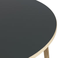 Round table with a smooth black top and natural wood trim, showcasing a minimalist design and modern aesthetics.