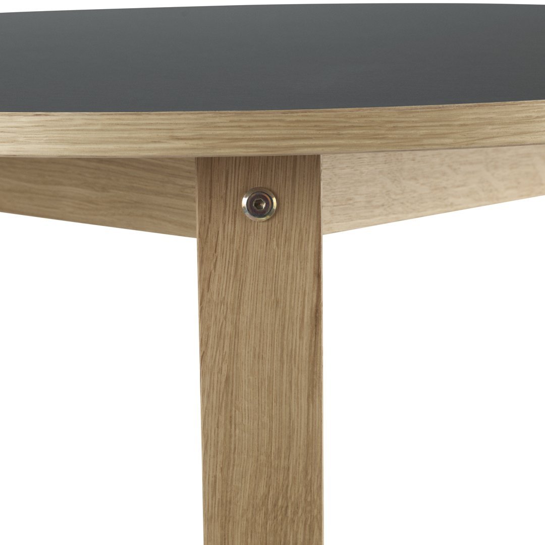"Round table with a sleek black top and natural oak legs, featuring a minimalist design and clean lines."
