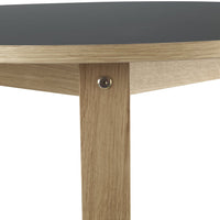 "Round table with a sleek black top and natural oak legs, featuring a minimalist design and clean lines."