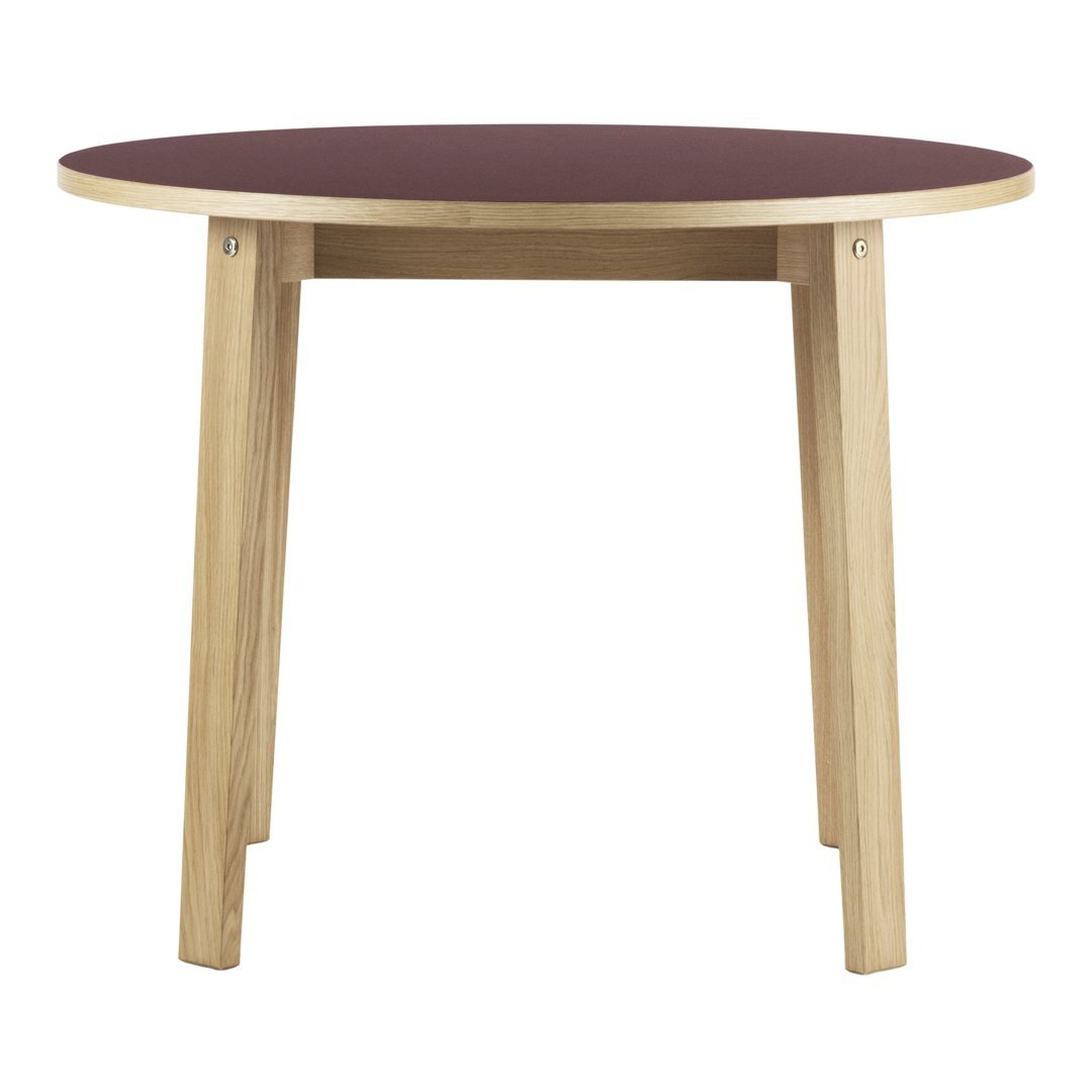 Round table with a burgundy top and natural wood legs, featuring a simple, modern design.