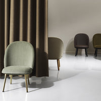 Stylish chairs in muted green, brown, and olive hues with smooth, modern designs against a neutral backdrop.