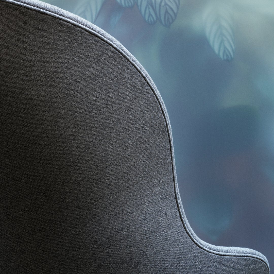 Dark gray fabric with a smooth, wavy edge and light gray trim against a soft, blurred background.