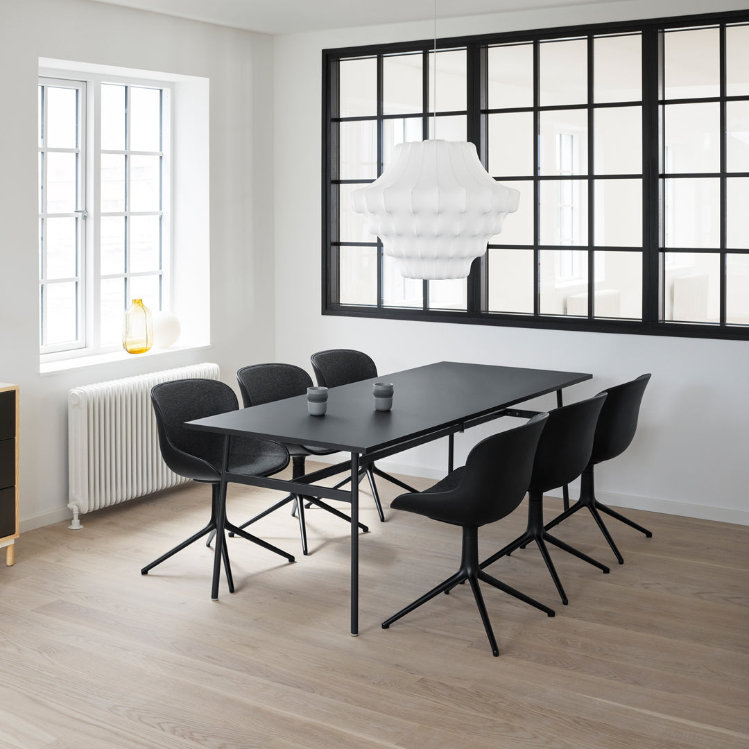 Modern black dining table with matching chairs, featuring a sleek design and neutral tones in a bright interior.