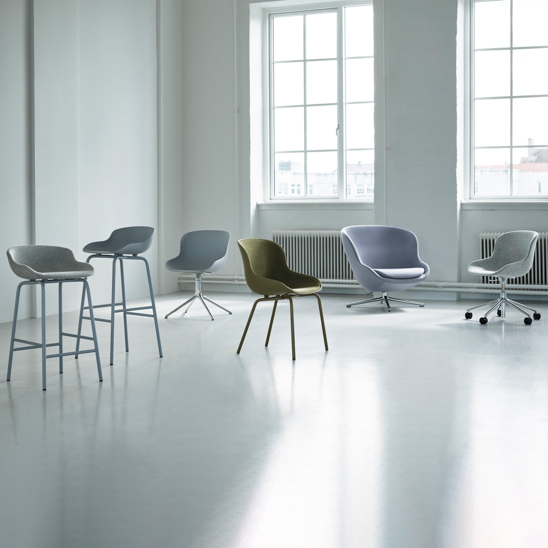Modern chairs in gray, olive green, and soft lavender, set against a bright, minimalist white background.