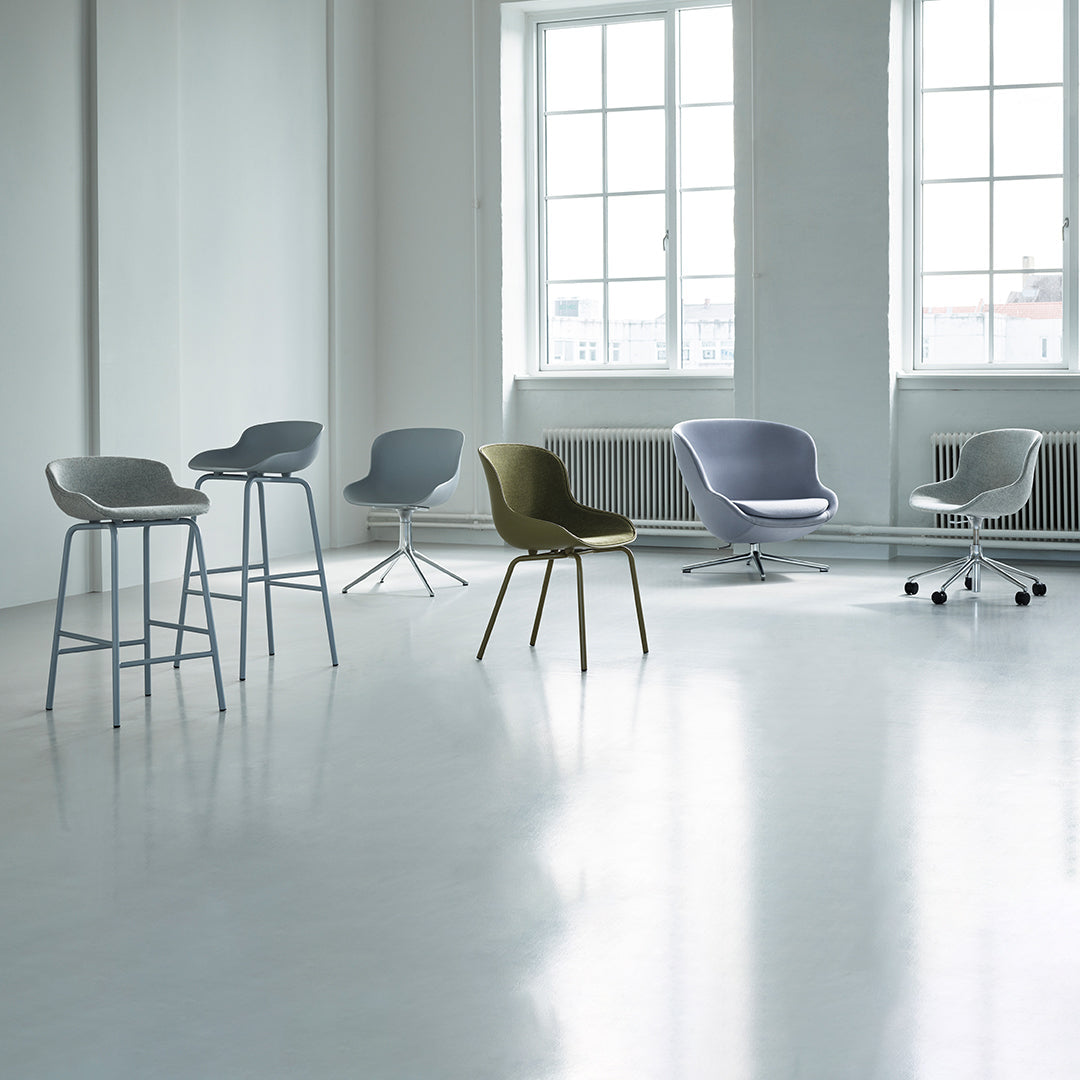 "Modern chairs in various pastel hues and sleek designs arranged in a bright, minimalistic interior setting."