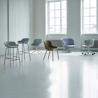 "Modern chairs in various pastel hues and sleek designs arranged in a bright, minimalistic interior setting."