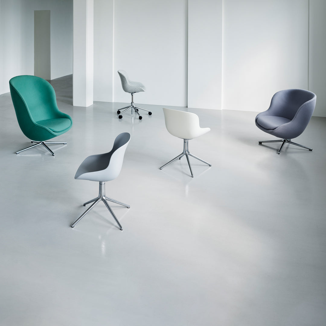 Modern chairs in teal, gray, white, and purple with sleek bases on a minimalist, neutral floor.
