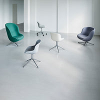 Modern chairs in green, grey, white, and navy blue against a minimalist gray floor, showcasing sleek, contemporary design.