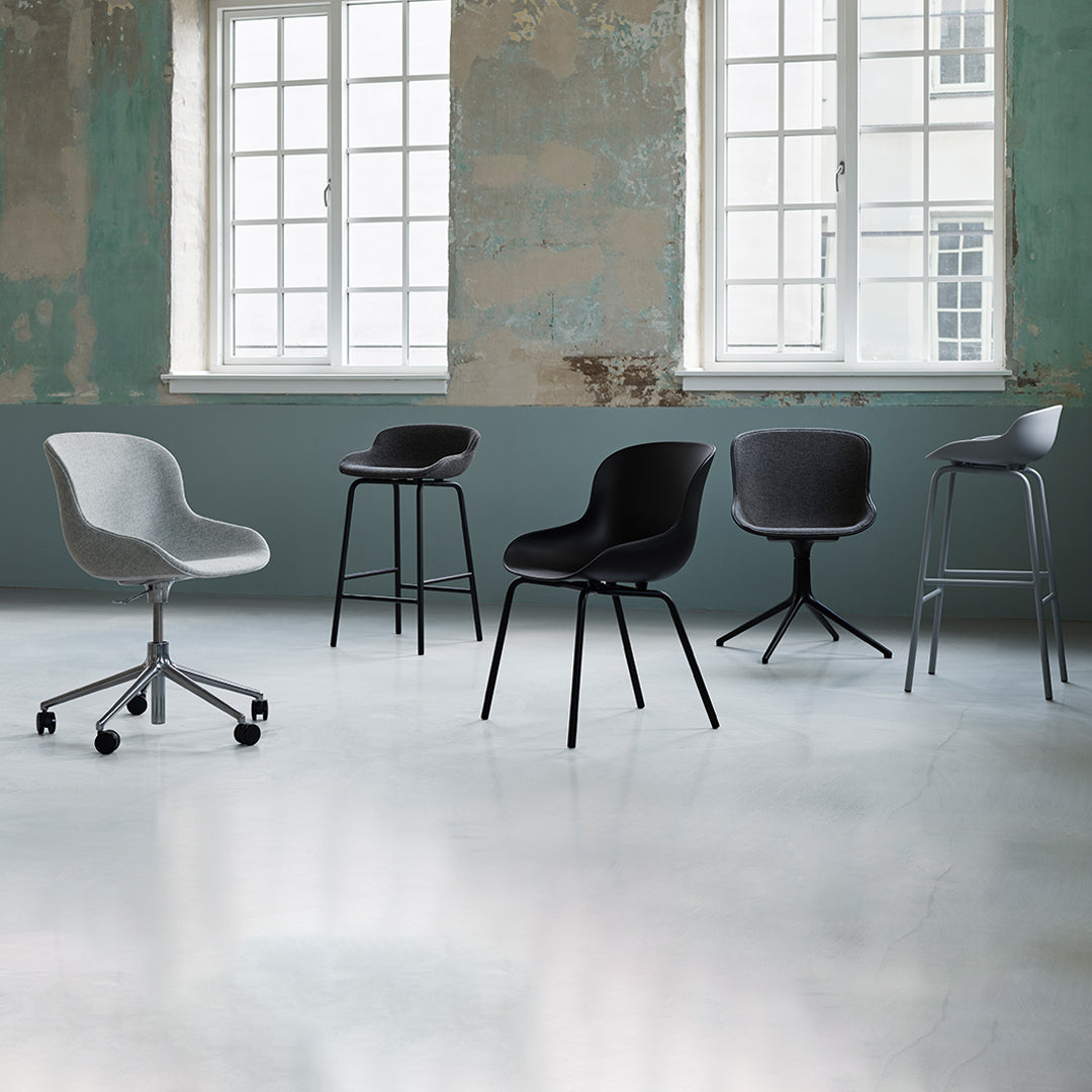 Stylish chairs in gray and black with sleek, modern designs, set against a distressed green wall backdrop.