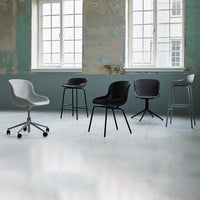 Stylish chairs in gray and black with sleek, modern designs, set against a distressed green wall backdrop.