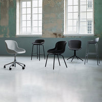 A collection of stylish chairs in gray and black, featuring sleek curves and minimalist designs against a textured wall.