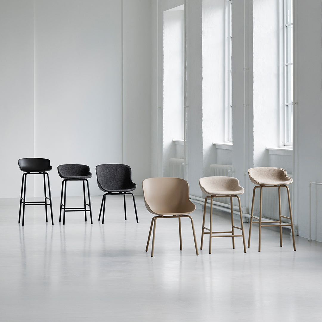 "Set of modern bar stools in black, beige, and soft tan with sleek, minimalist designs against a bright, airy backdrop."